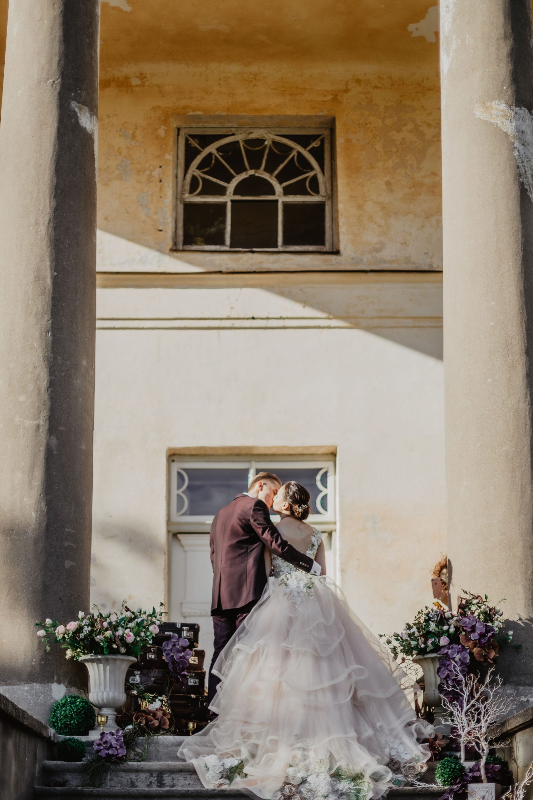 Jaunais pāris skūpstās uz Padures muižas kāpnēm starp klasicisma stila kolonnām.